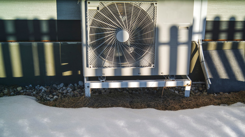 AC unit outside of a house, with melted snow around it
