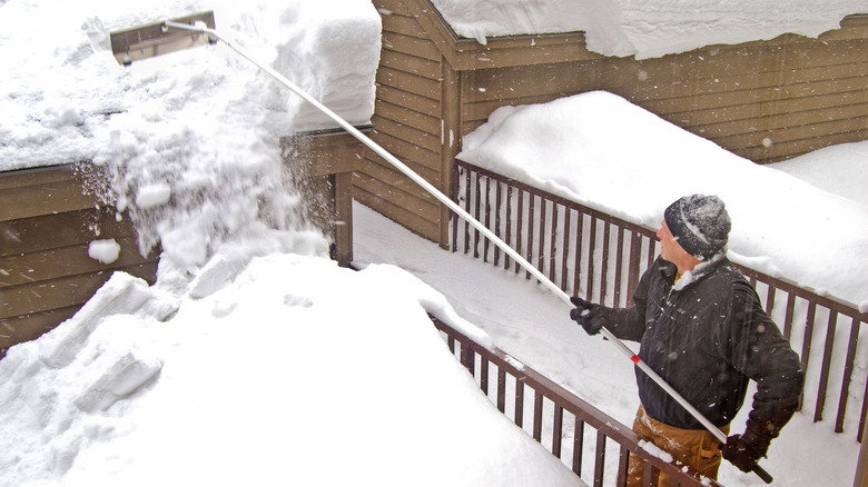 Person clears snow with a roof rake