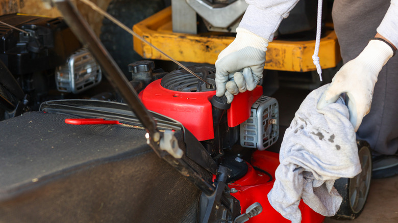 A landscaper checks the oil of their lawn mower after performing maintenance