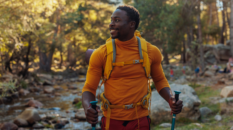 Hiker using backpack and trekking poles sold at REI