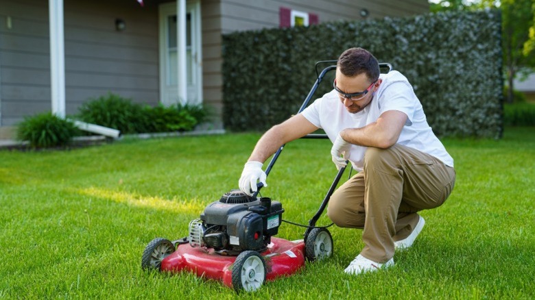 A man checking push mower components