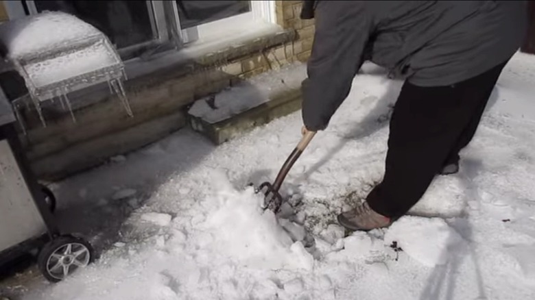 Man uses a pitchfork to remove ice from the ground