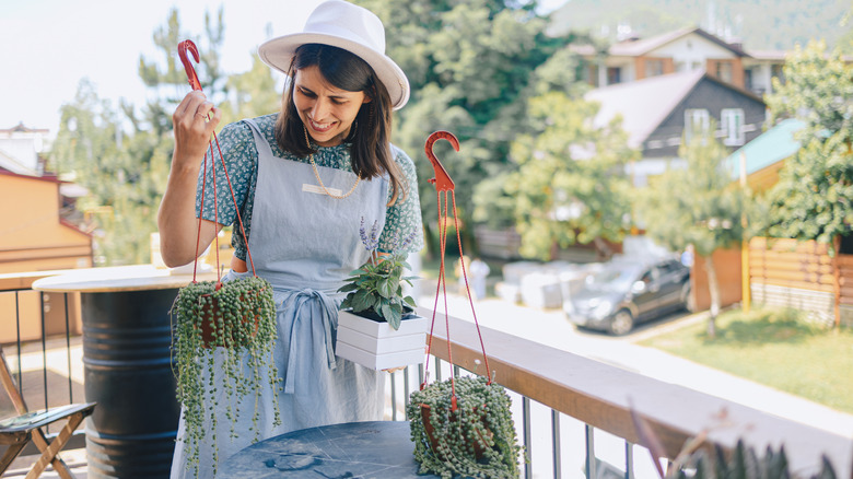 Woman preparing hanging plants on patio