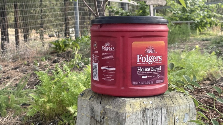 Folgers plastic coffee can on a post in a garden