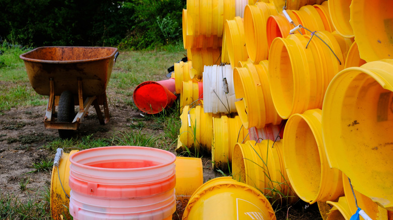 Stacks of 5-gallon buckets near a wheelbarrow