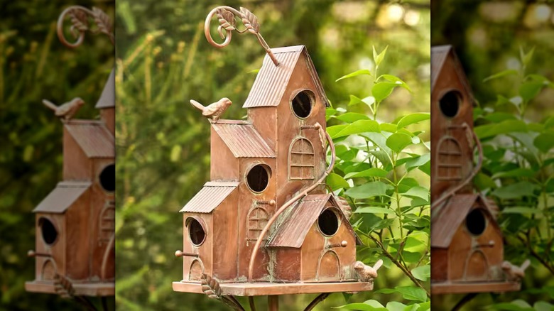 A copper color birdhouse used as a topper for a garden stake