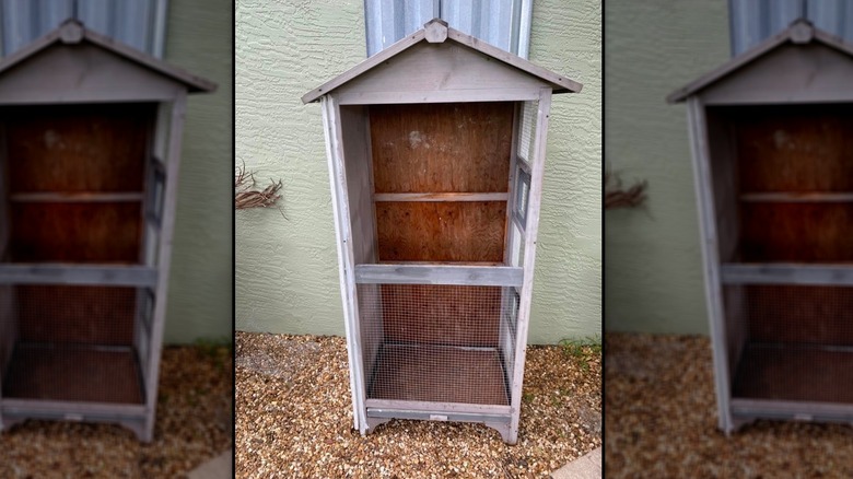 A wooden birdhouse repurposed to house garden tools and supplies