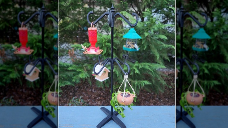An assortment of bird feeders and growing pods hanging from stake