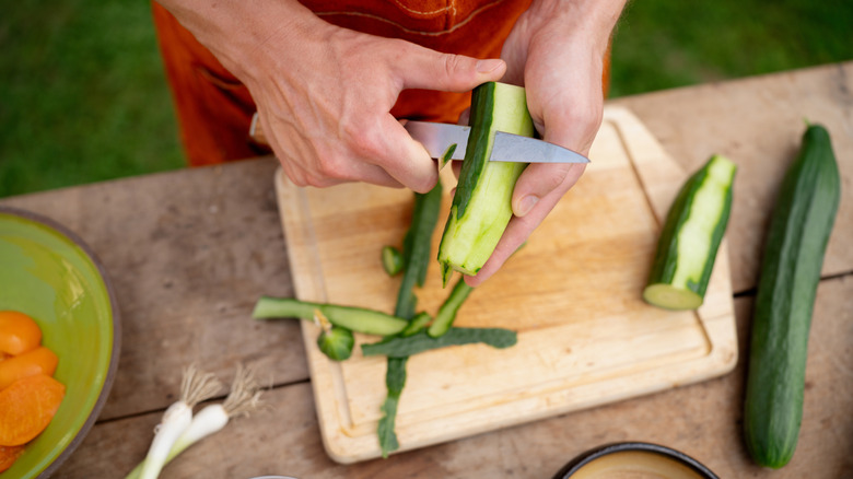 Person peeling cucumbers