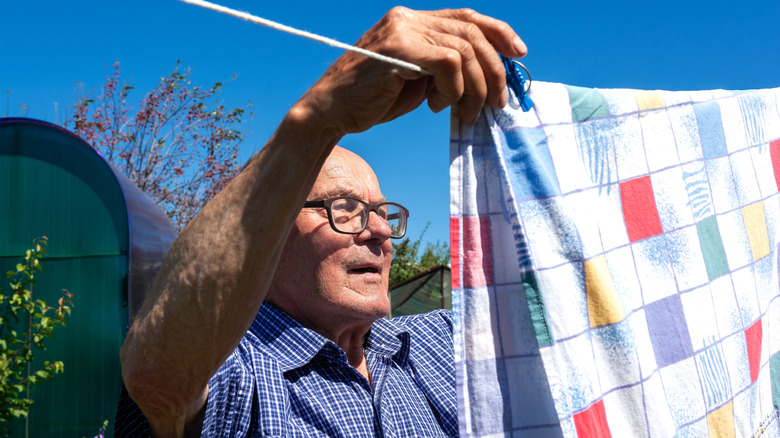 man hanging a bedsheet on a clothesline