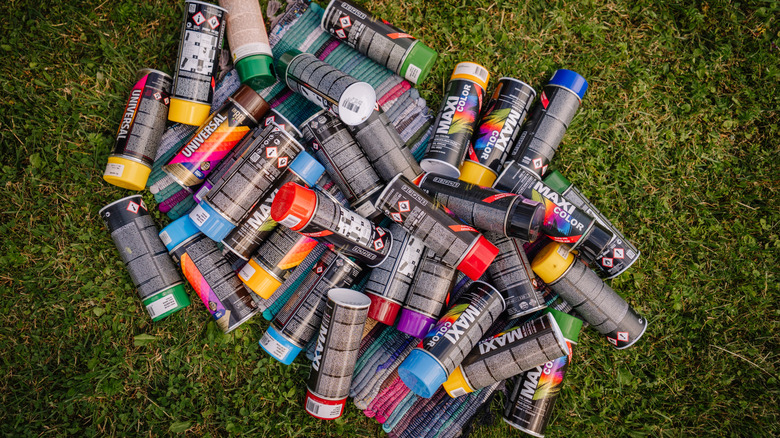 colorful spray paint cans with lids on grass