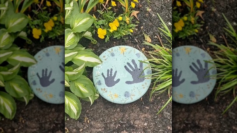 A painted cement stepping stone with handprints on it