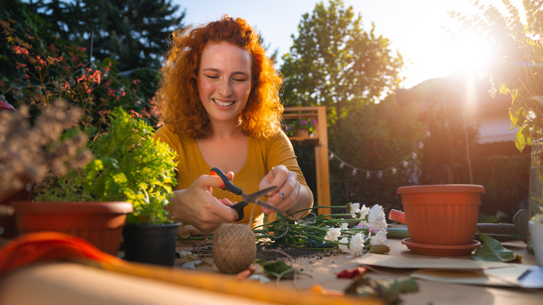 Smiling woman cutting yarn, preparing planter