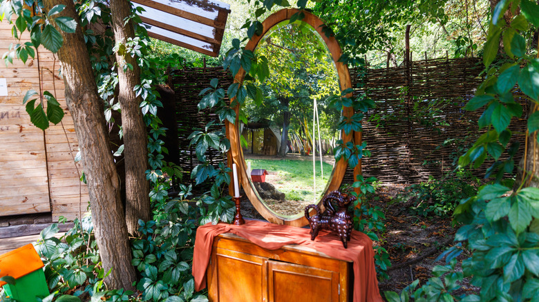 A vintage vanity mirror in a garden, reflecting the yard