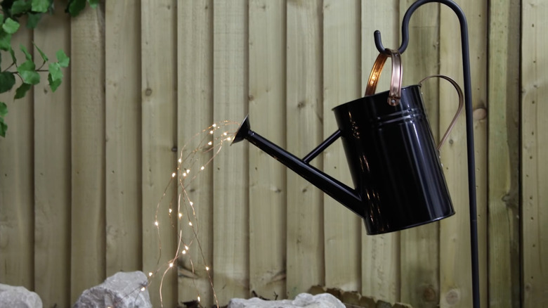 A watering can with fairy lights pouring out of the spout