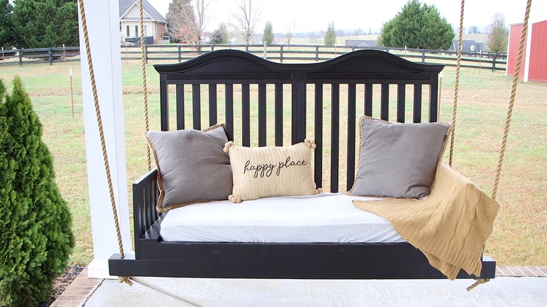 A porch swing built from a dark wood crib