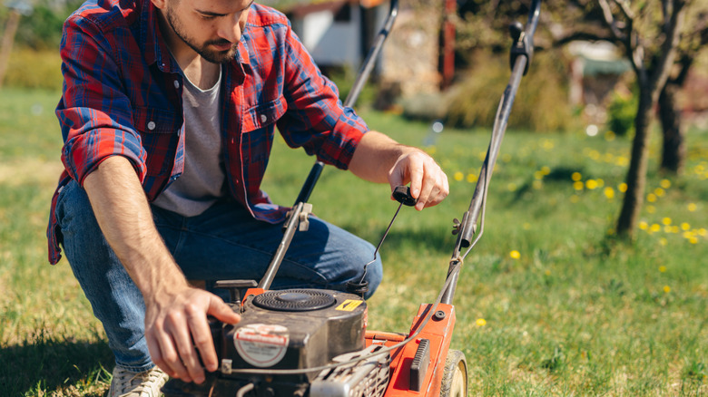 Man checks oil level in lawn mower