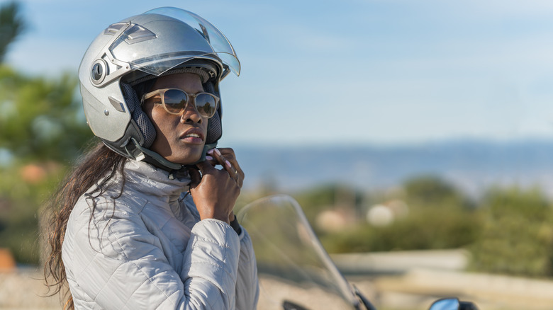 woman outside putting on helmet