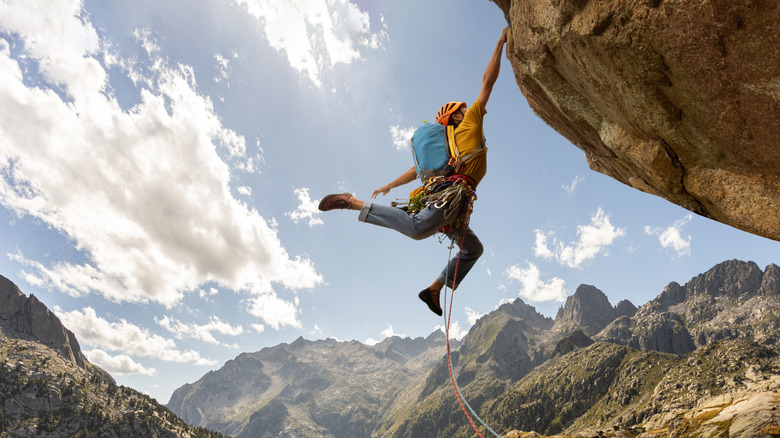Rock climber hanging on the edge of a crag