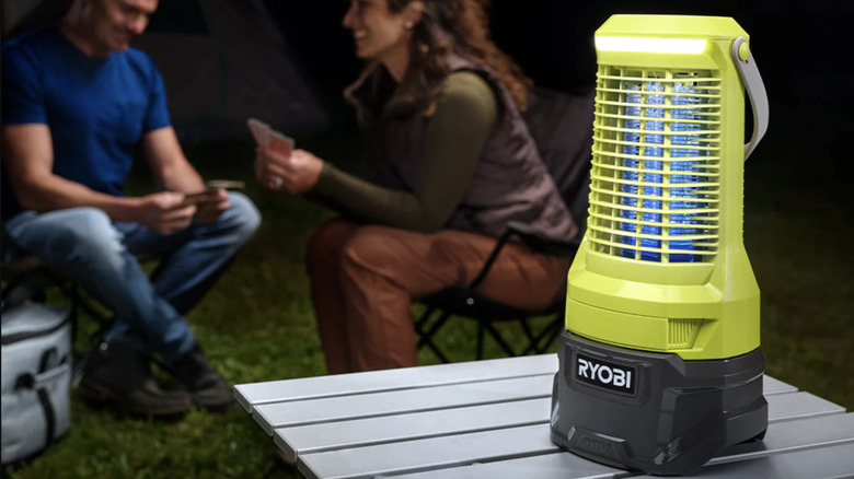 The Ryobi 18V ONE+ bug zapper on a table outside while couple relaxes