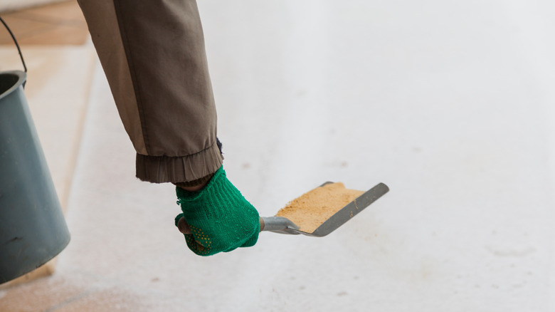 sprinkling sand on snowy driveway