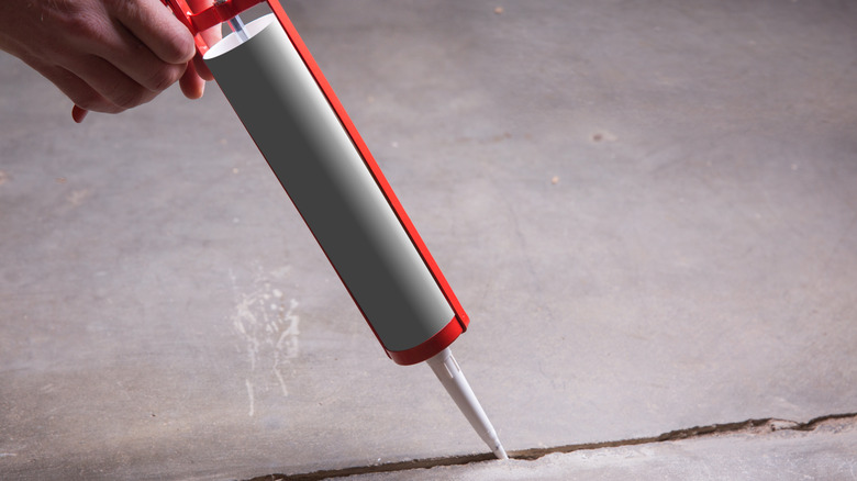 Person caulking a concrete driveway crack