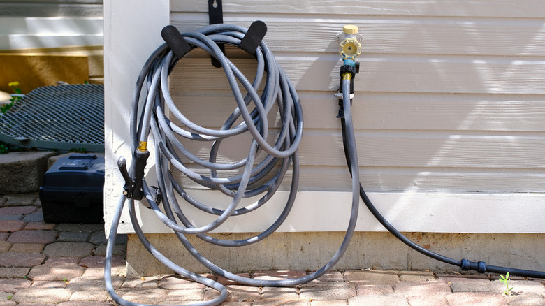 Tangled garden hose on the side of a house
