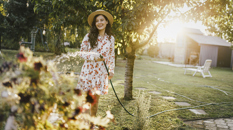 Woman watering plants with hose