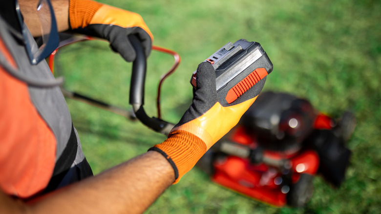 Person looking at lawn mower battery
