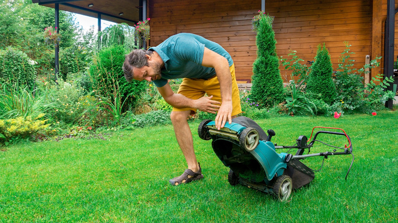 Person trying to figure out what's wrong with the lawn mower