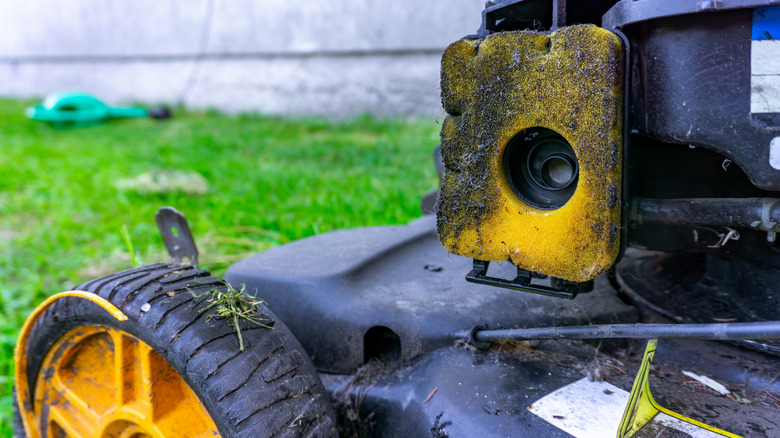 A dirty black and yellow lawn mower air and an air filter.