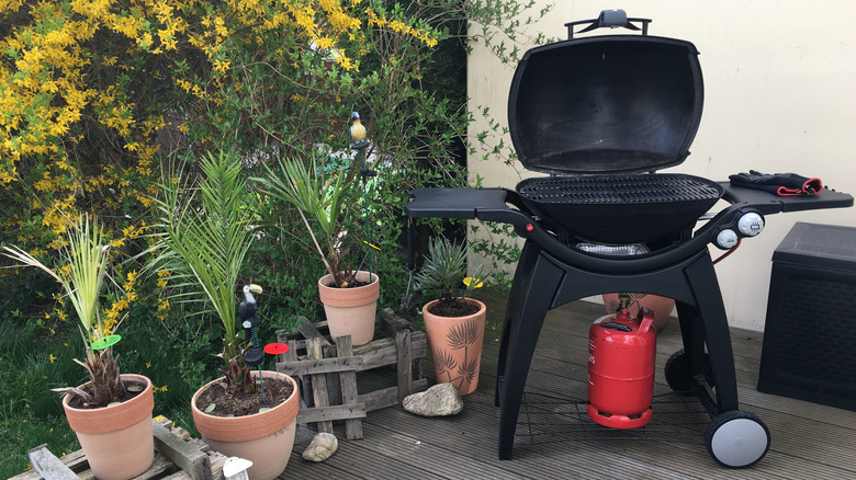A gas barbecue with orange gas bottle on a patio
