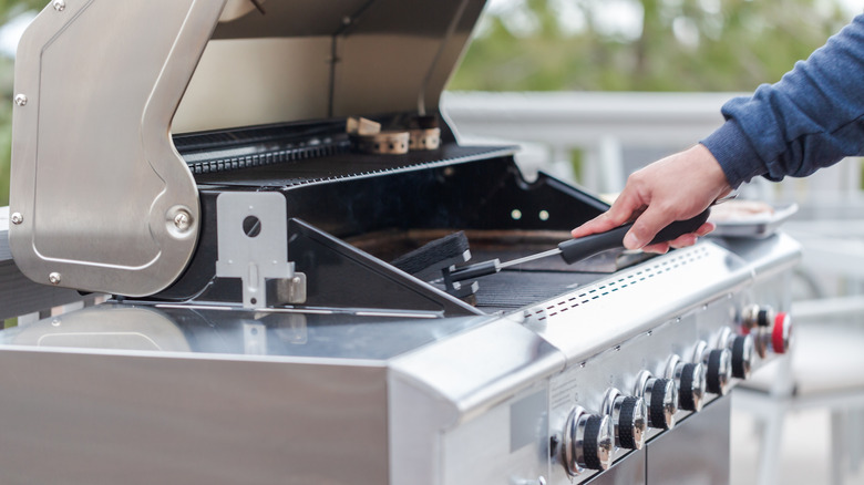 A person cleaning an outdoor grill