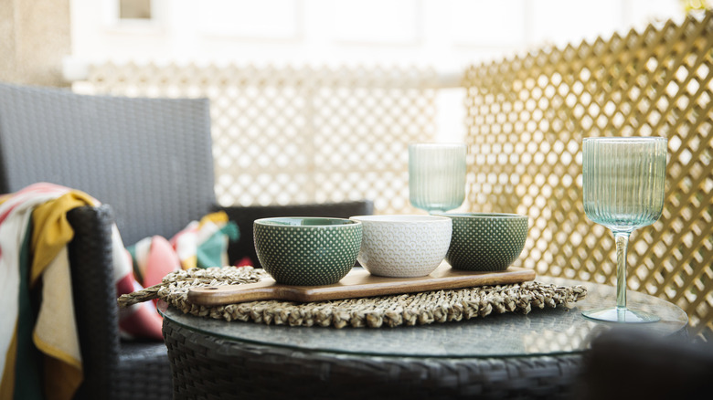 Dishes, placemat, and blanket on patio furniture