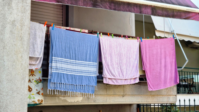 Multiple towels hung over a balcony railing