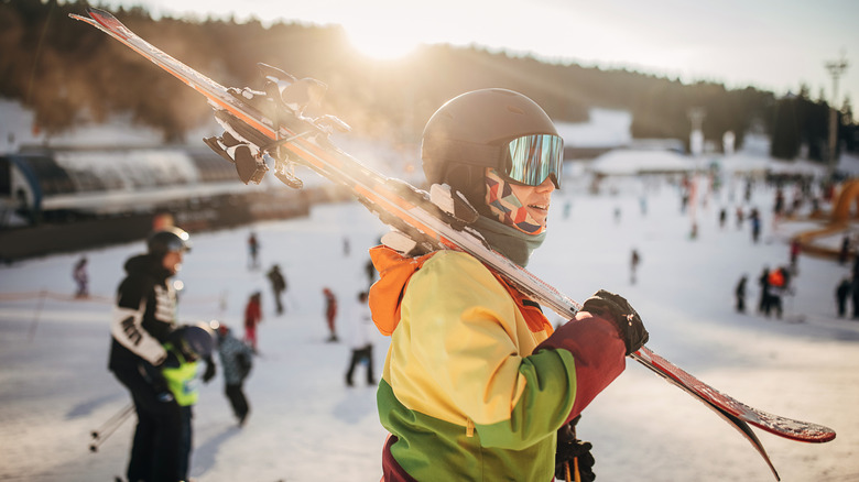 Skier wearing a helmet and carrying skis