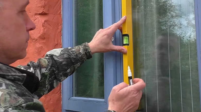 Person adding thin white stripes to window glass