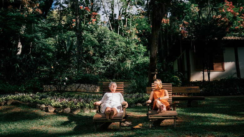Two women lounging on chairs outside in garden