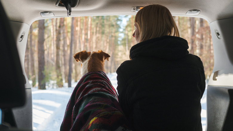 Woman and dog car camping in snow