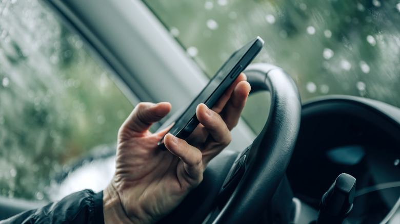 Person dialing phone from inside car