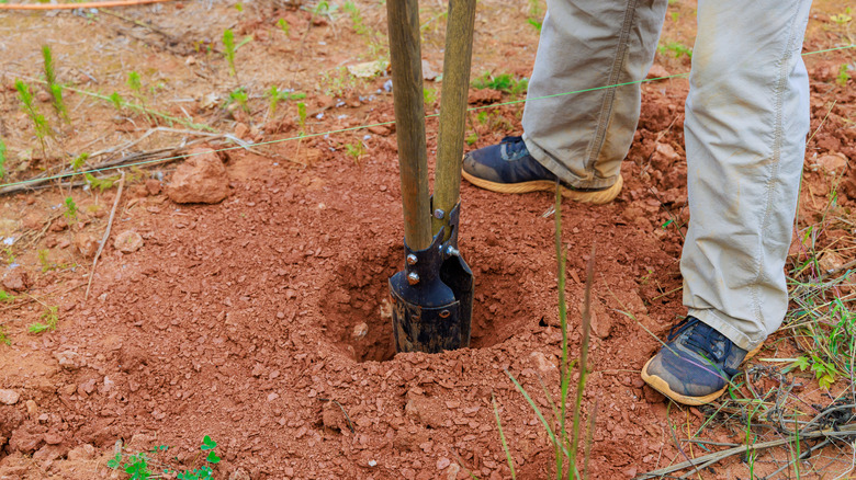 A man using a post hole digger tool