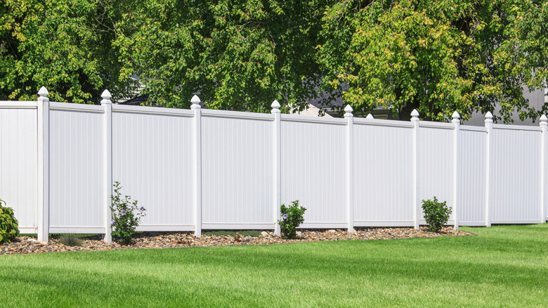 A white vinyl fence running across a garden