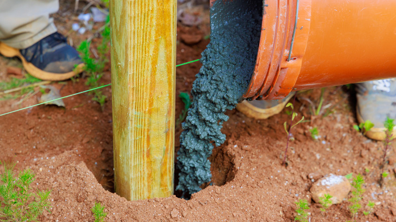 Concrete being poured around a newly-sunk fence post