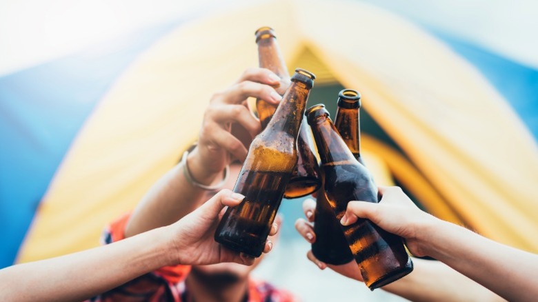 A group of campers toasting with bottles of beer