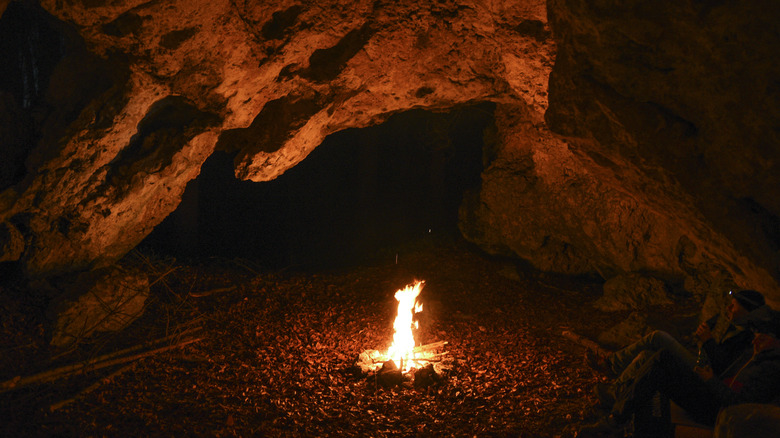 A dark cave with a campfire burning inside