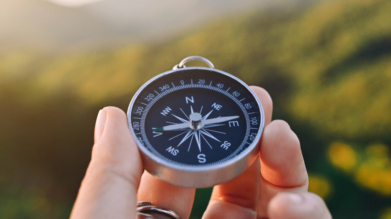A person's hand holding a compass