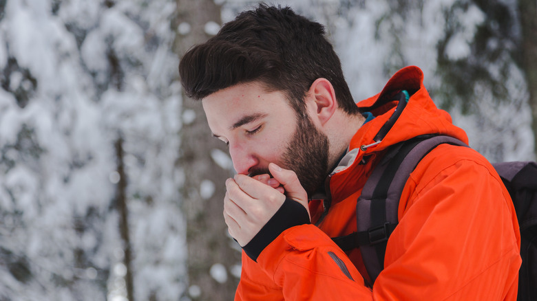 A cold man in an orange jacket with no hat on