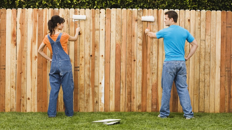 Couple painting fence