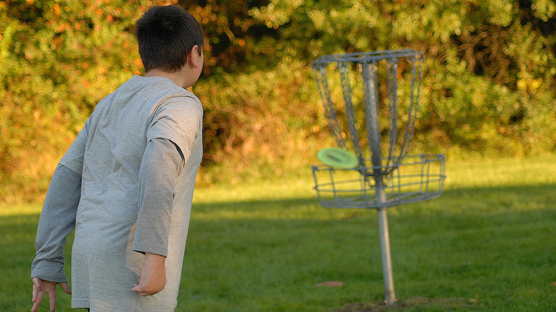 A boy watches his putt enter a basket