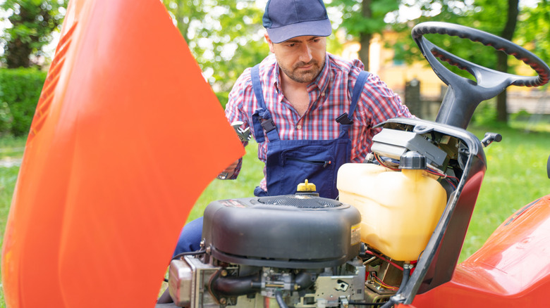 Man working on riding lawn mower engine